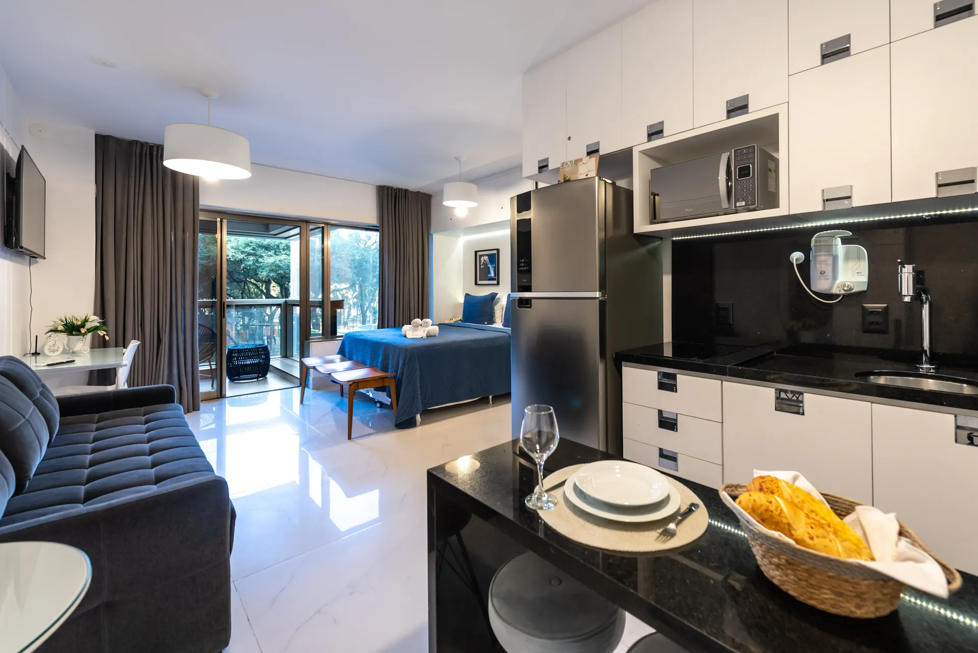 Cozinha integrada com sala do Apartamento 112 Rosemari, equipada com fogão, geladeira e bancada